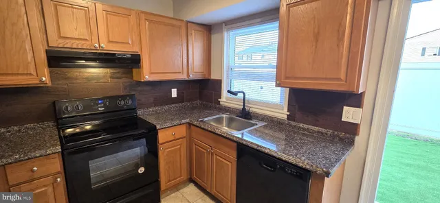 a kitchen with granite countertop a sink stove and cabinets