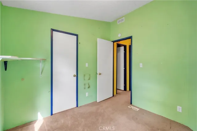 a view of an empty room with closet and wooden floor