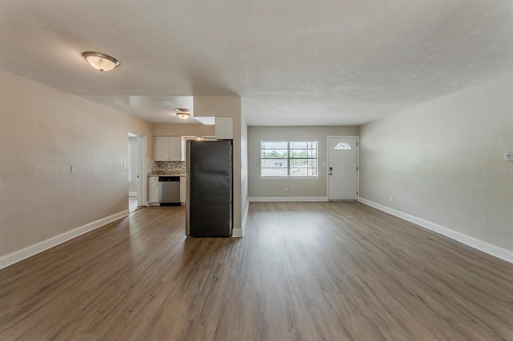 5500 Riviera Drive Orlando, FL 32808 - Photo 14 of 48 an empty room with wooden floor kitchen view and windows