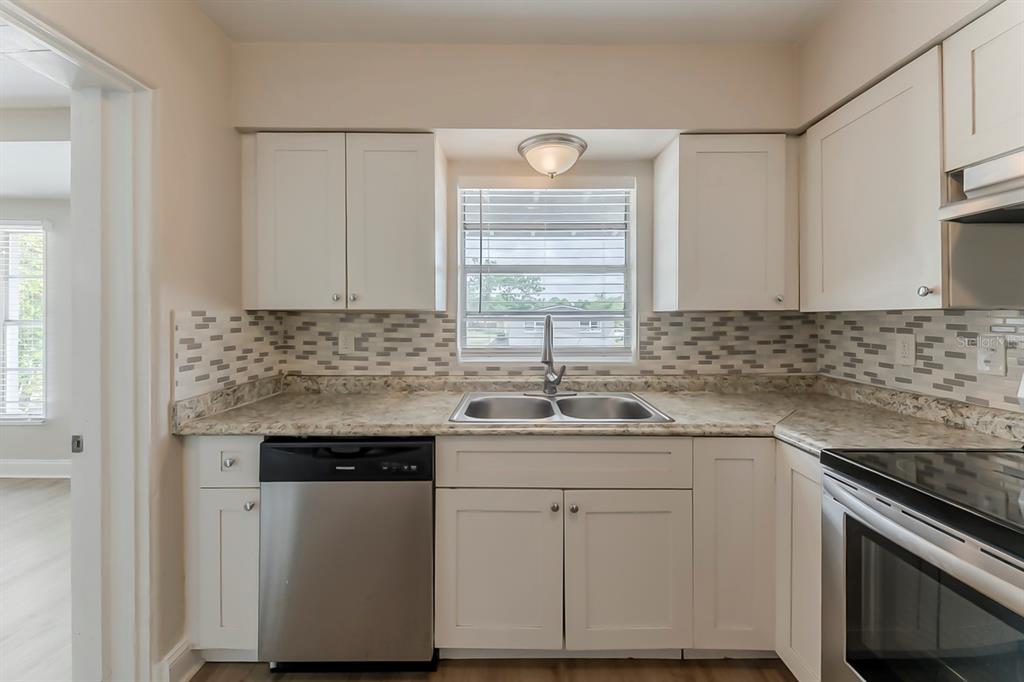 5500 Riviera Drive Orlando, FL 32808 - Photo 8 of 48 a kitchen with white cabinets appliances a sink and a window