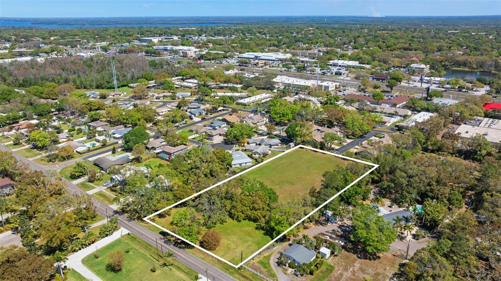an aerial view of a residential houses with outdoor space and trees