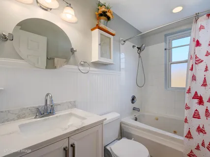 a bathroom with a sink vanity mirror and bathtub