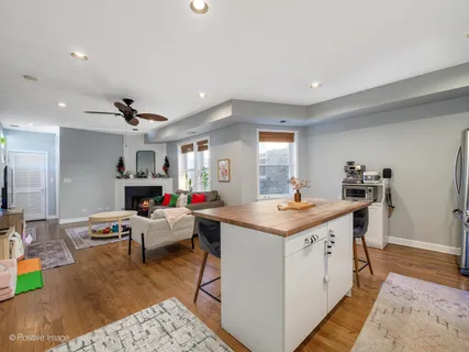 a living room with stainless steel appliances furniture a rug and a kitchen view