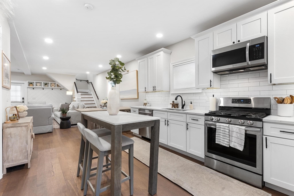 43 Alfred Street, Unit A Everett, MA 02149 - Photo 15 of 29 a kitchen with stainless steel appliances a stove top oven a sink dishwasher and white cabinets with wooden floor