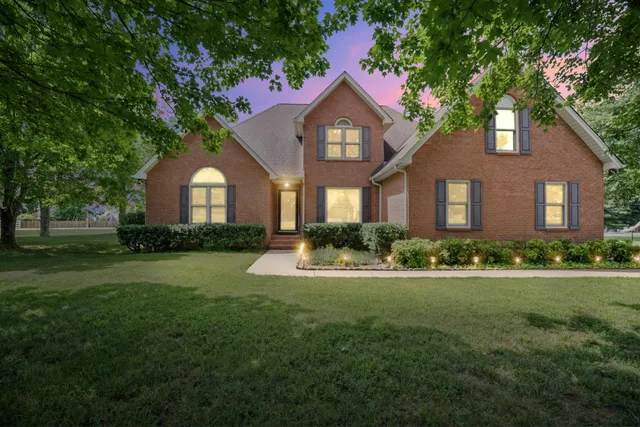 a front view of a house with a garden and trees