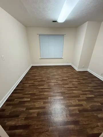 a view of an empty room with closet and wooden floor