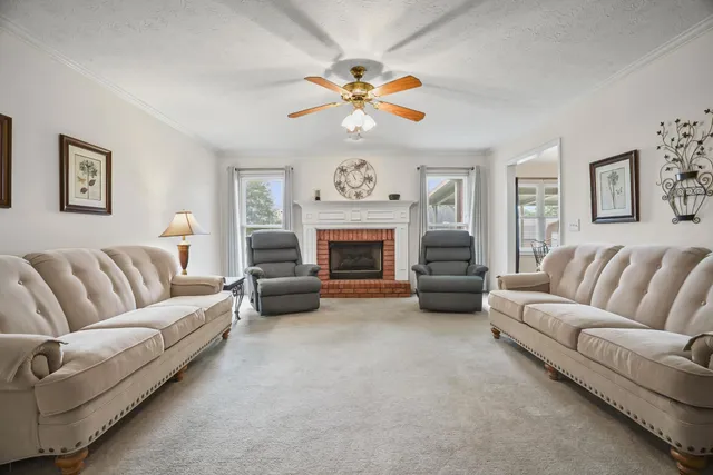 a living room with furniture a fireplace and a ceiling fan