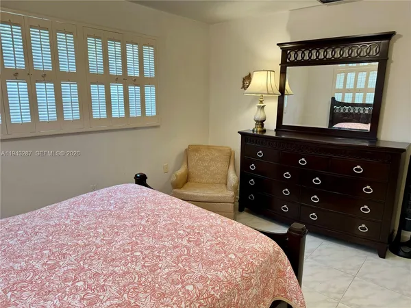 a bedroom with a bed a mirror on dresser and a window