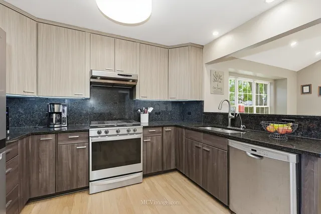 a kitchen with stainless steel appliances granite countertop a stove a sink and a microwave