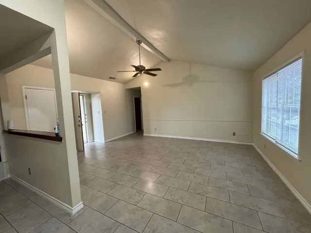 en empty room with a ceiling fan and carpet