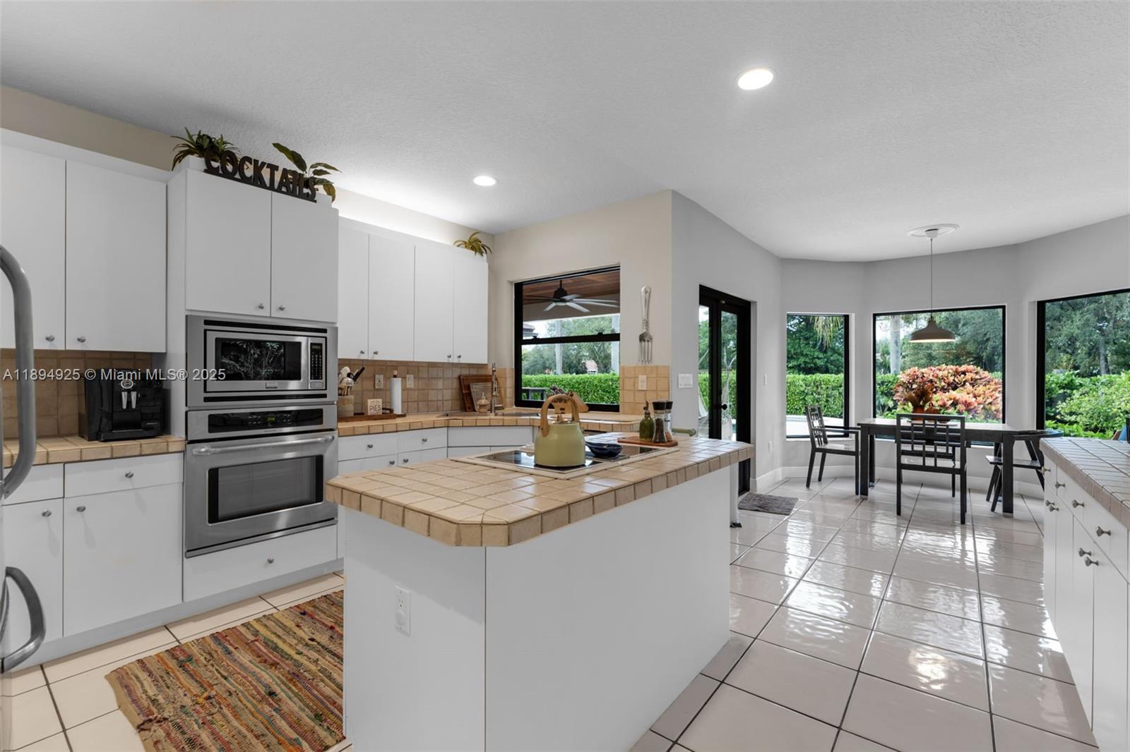 12019 Southwest 77th Terrace Miami, FL 33183 - Photo 12 of 67 a kitchen with stainless steel appliances granite countertop a stove top oven a sink dishwasher a dining table and chairs with wooden floor