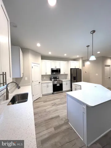 a kitchen with stainless steel appliances kitchen island granite countertop a sink a stove a refrigerator and island with wooden floor