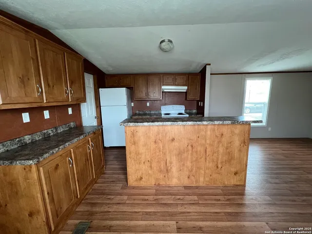 a kitchen with granite countertop a stove top oven a sink dishwasher and cabinets with wooden floor