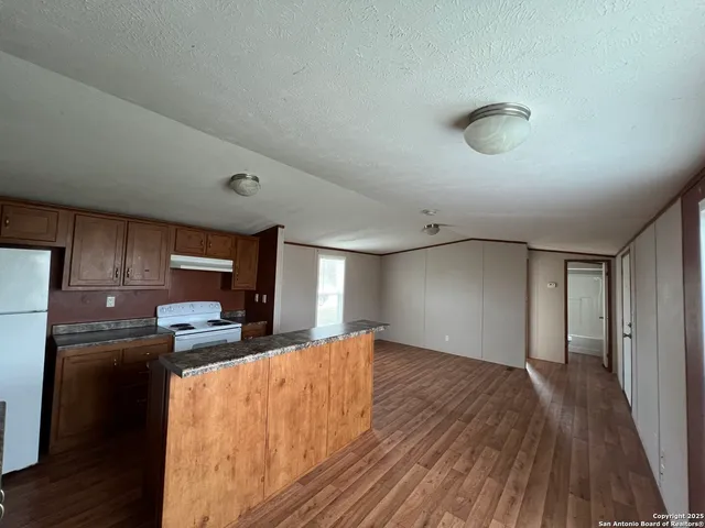 a kitchen with stainless steel appliances kitchen island granite countertop a refrigerator oven a sink dishwasher and a stove with wooden floor