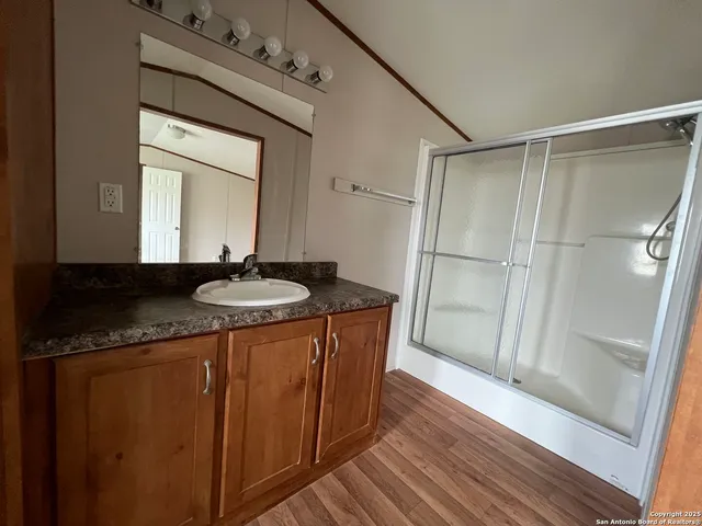a bathroom with a granite countertop sink a mirror and shower