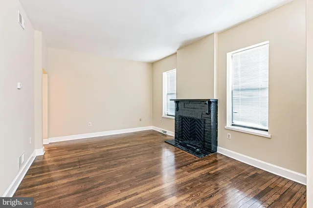 an empty room with wooden floor a fireplace and windows