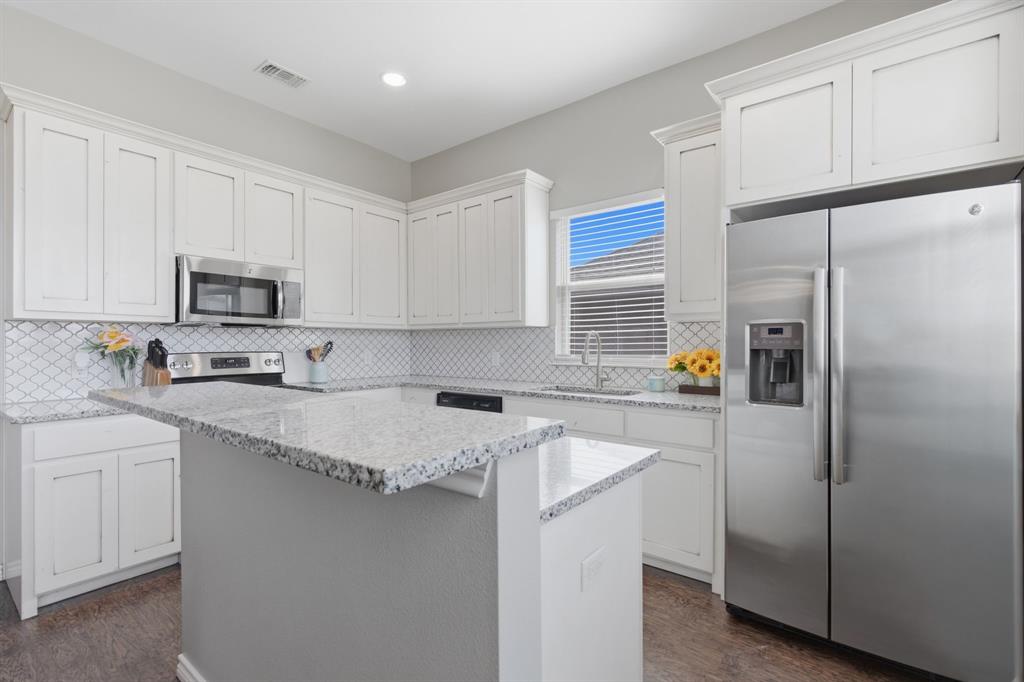 711 Hadley Lane Valley View, TX 76272 - Photo 9 of 40 Kitchen with stainless steel appliances, white cabinetry, a center island, and light stone counters
