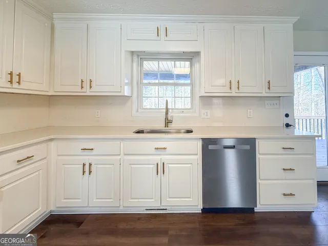 a kitchen with white cabinets and sink