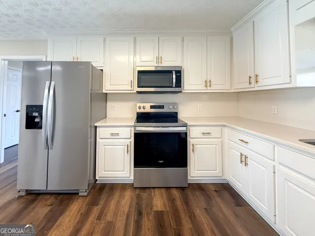 a kitchen with granite countertop white cabinets and stainless steel appliances
