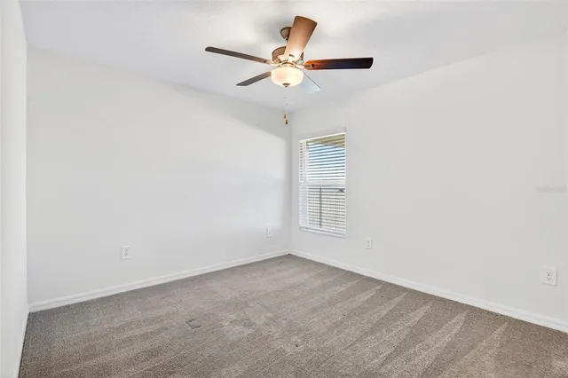 an empty room with a ceiling fan and window