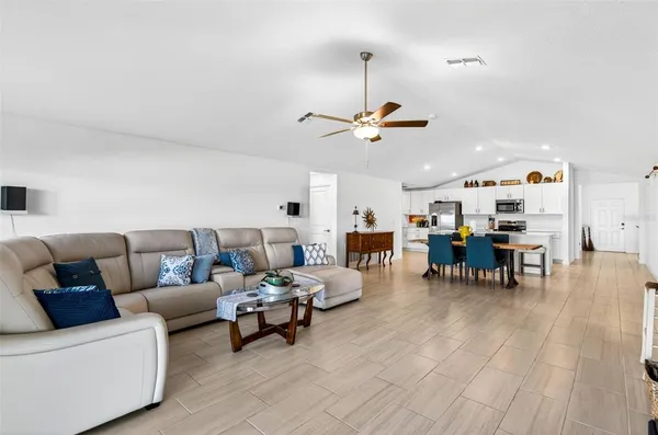 a living room with furniture a flat screen tv and a ceiling fan