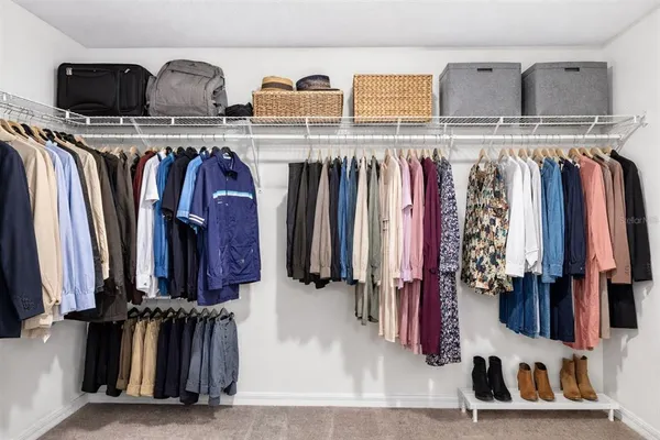 a view of walk in closet with clothes and shoes