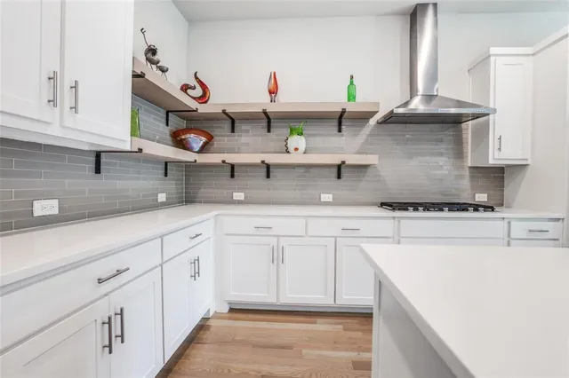 a kitchen with stainless steel appliances granite countertop a sink white cabinets and a wooden floors