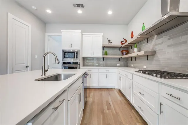 a kitchen with granite countertop a sink stainless steel appliances and cabinets
