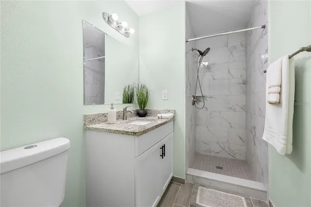 a bathroom with a granite countertop sink a mirror and shower