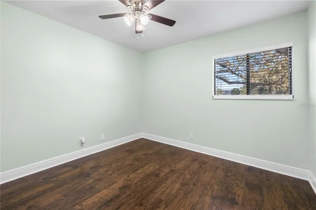 an empty room with wooden floor closet and windows