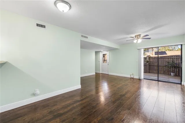 an empty room with wooden floor mirror and windows