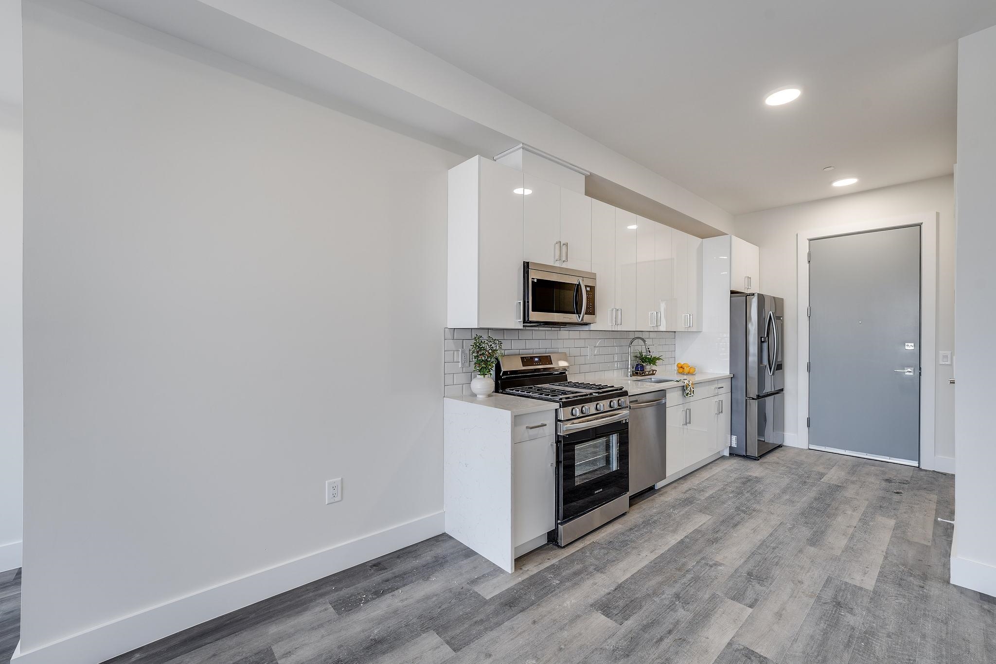 a kitchen with stainless steel appliances a stove top oven a refrigerator a sink and dishwasher