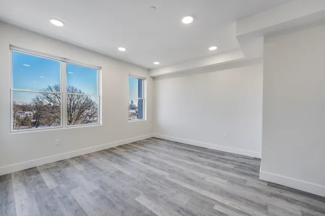 a view of an empty room with wooden floor and window
