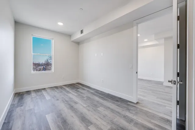 an empty room with wooden floor and windows