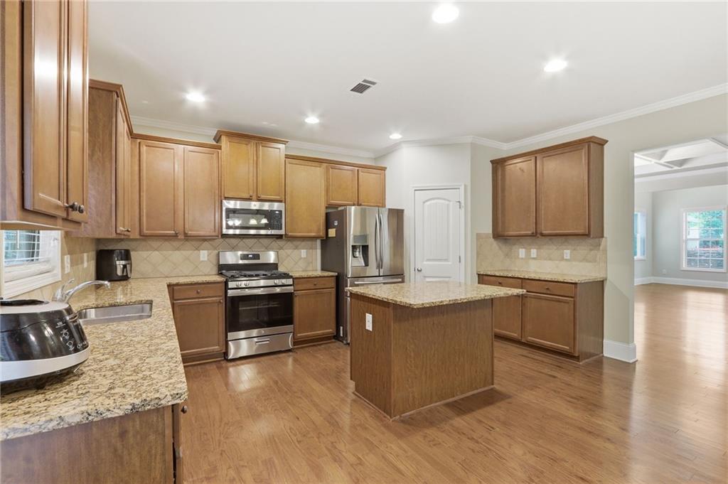 1515 Riva Ridge Suwanee, GA 30024 - Photo 13 of 35 a kitchen with stainless steel appliances granite countertop a stove top oven a sink dishwasher a refrigerator and cabinets with wooden floor