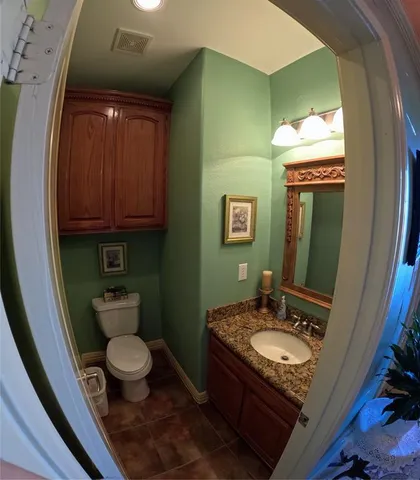 a bathroom with a granite countertop toilet sink and mirror