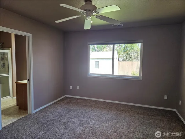 an empty room with a window and a fan