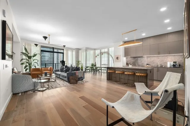 a living room with furniture a rug kitchen view and a large window