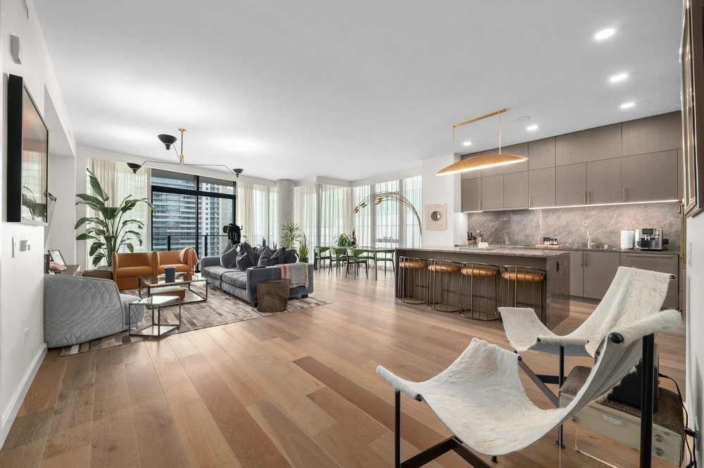 a living room with furniture a rug kitchen view and a large window