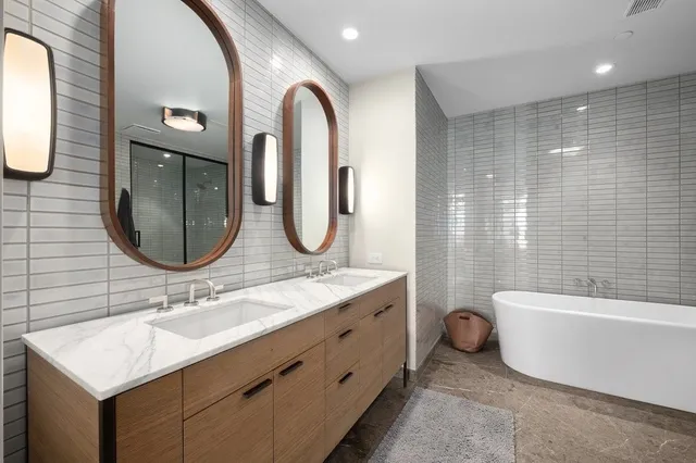a bathroom with a double vanity sink a toilet and a bathtub