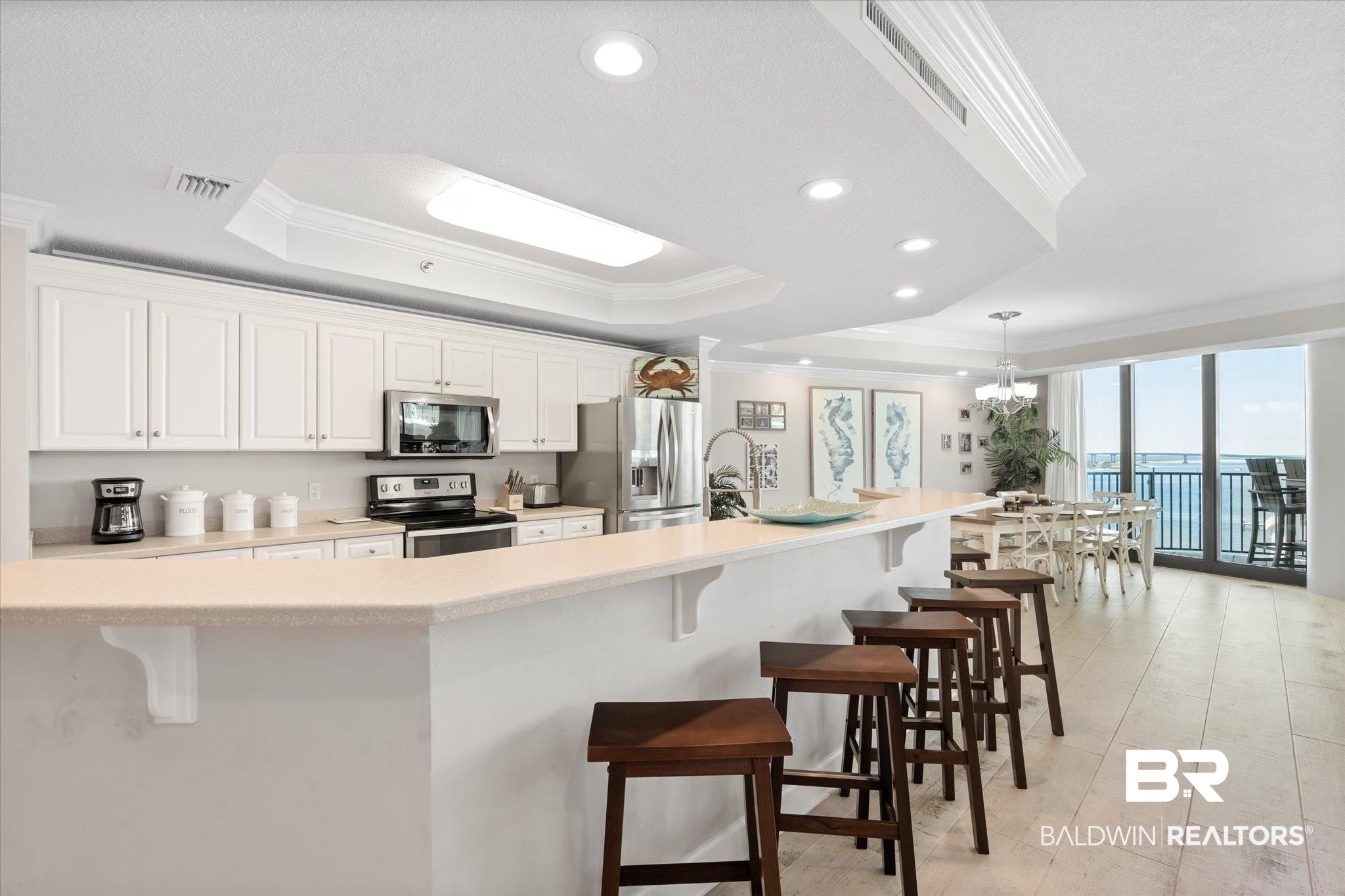 27582 Canal Road, Unit 2611 Orange Beach, AL 36561 - Photo 10 of 37 Kitchen with appliances with stainless steel finishes, a raised ceiling, and a kitchen breakfast bar