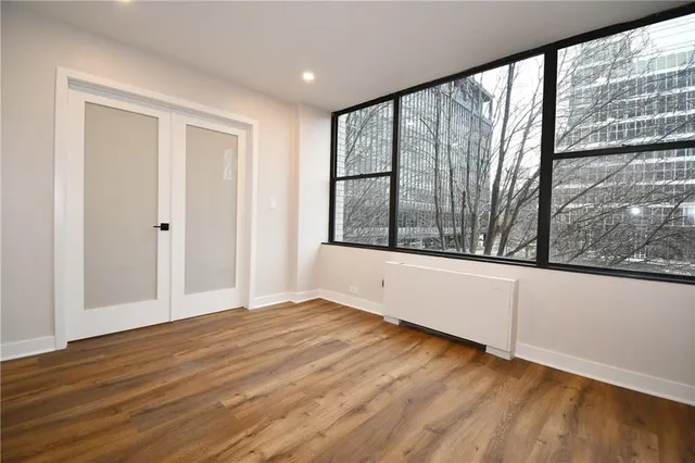 a view of an empty room with wooden floor and a window