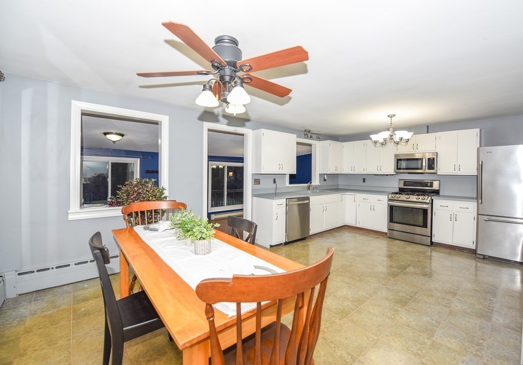 63 Kemp Street Groton, MA 01450 - Photo 2 of 24 a kitchen with stainless steel appliances kitchen island granite countertop a refrigerator a stove a sink dishwasher and a dining table with wooden floor