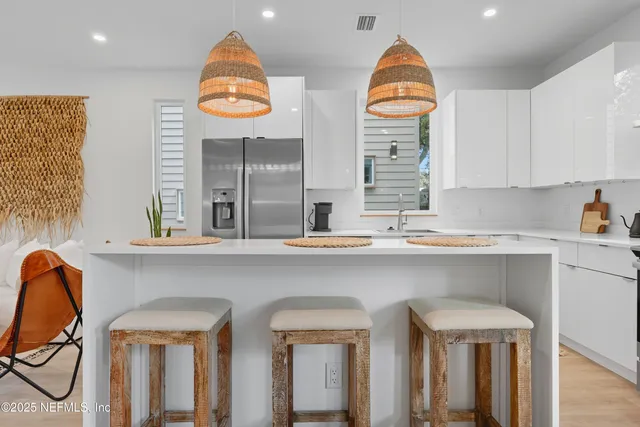 a kitchen with stainless steel appliances granite countertop a sink a window and white cabinets