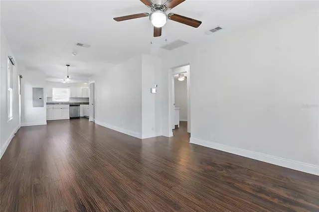 a view of an empty room with a window and wooden floor