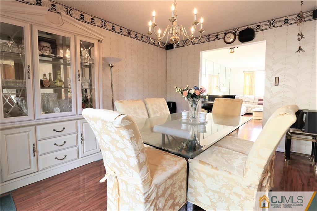 6801 Hana Road Edison, NJ 08817 - Photo 8 of 24 a dining room with wooden floor a chandelier a wooden table and chairs