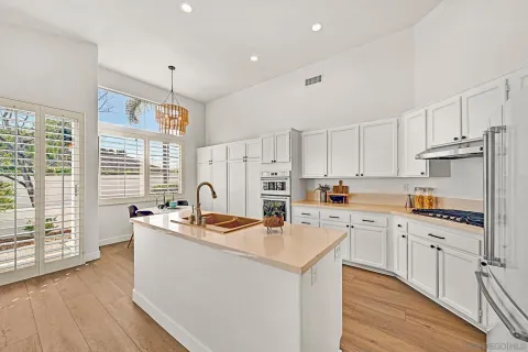 a kitchen with stainless steel appliances granite countertop a sink a stove a refrigerator cabinets and a dining table