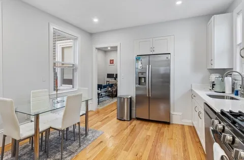 a kitchen with stainless steel appliances granite countertop a refrigerator a stove a sink dishwasher and a dining table with wooden floor