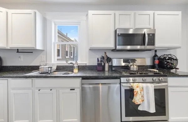 a kitchen with stainless steel appliances granite countertop a sink a stove and microwave