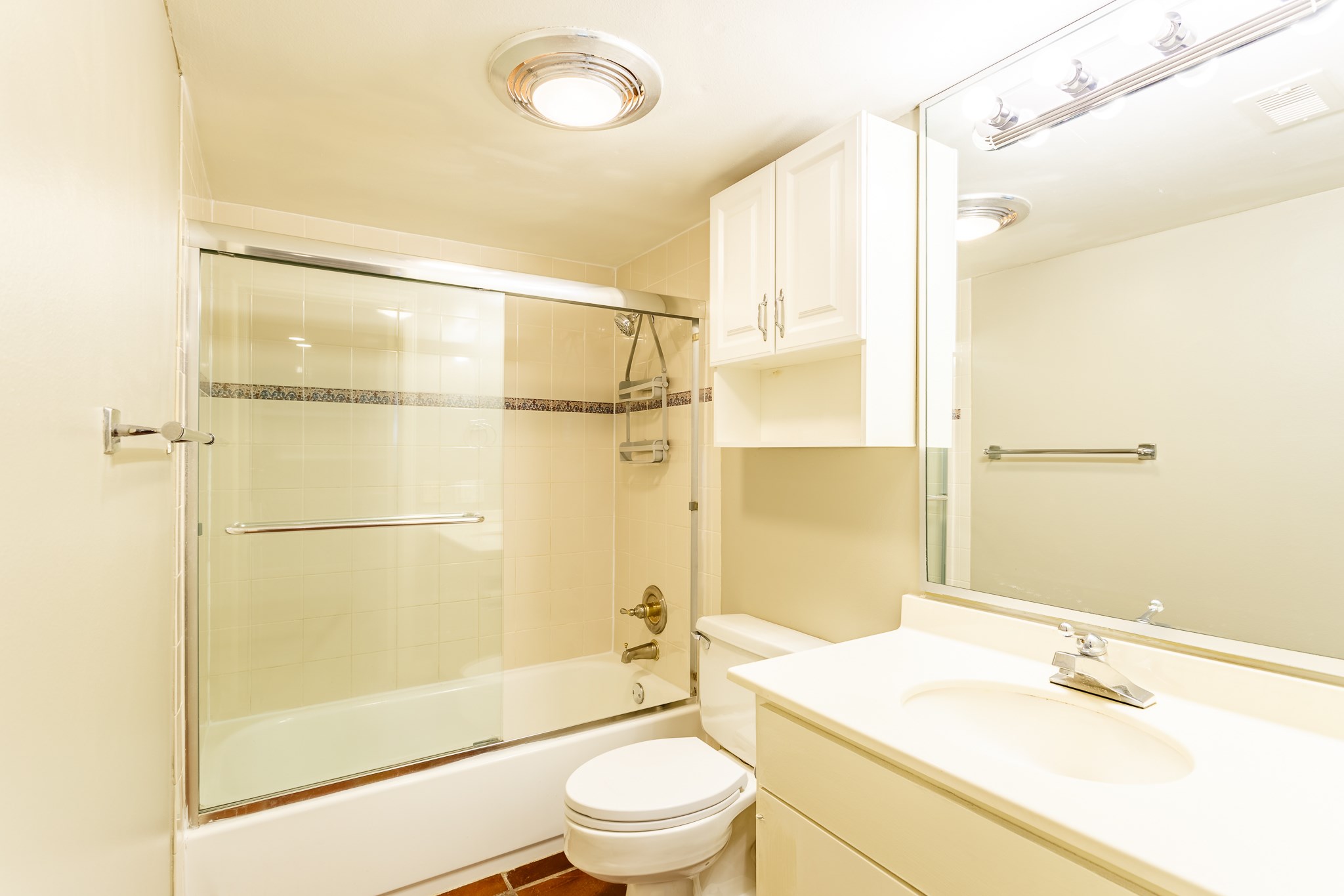 2349 Albans Road, Unit 1 Houston, TX 77005 - Photo 11 of 14 This is a bright, clean bathroom featuring a bathtub with a glass sliding door, a modern sink with a large mirror, overhead lighting, and ample storage space.